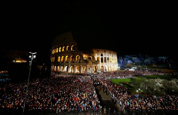 Faithful stand as Pope Francis leads the Via Crucis (Way of the Cross) procession during Good Friday celebrations at the Colosseum in Rome