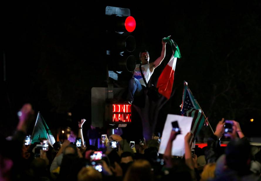 A demonstrator climbs a traffic light outside Republican U.S. presidential candidate Donald Trump's campaign rally in Costa Mesa