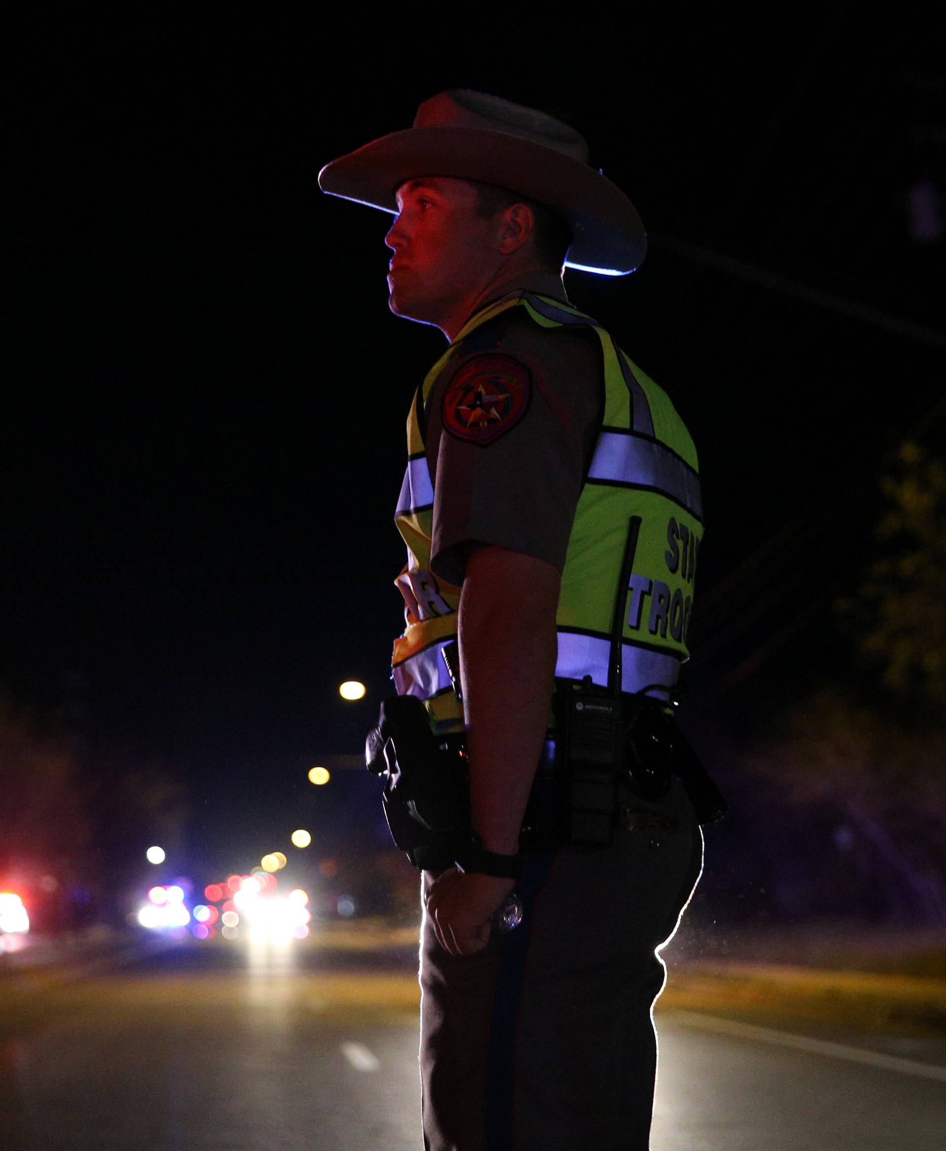 A Texas state trooper keeps watch at a checkpoint as nearby law enforcement personnel investigate an incident in Austin