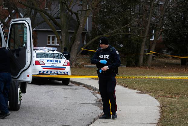 Police officers guard the grounds of a house they searched in Toronto