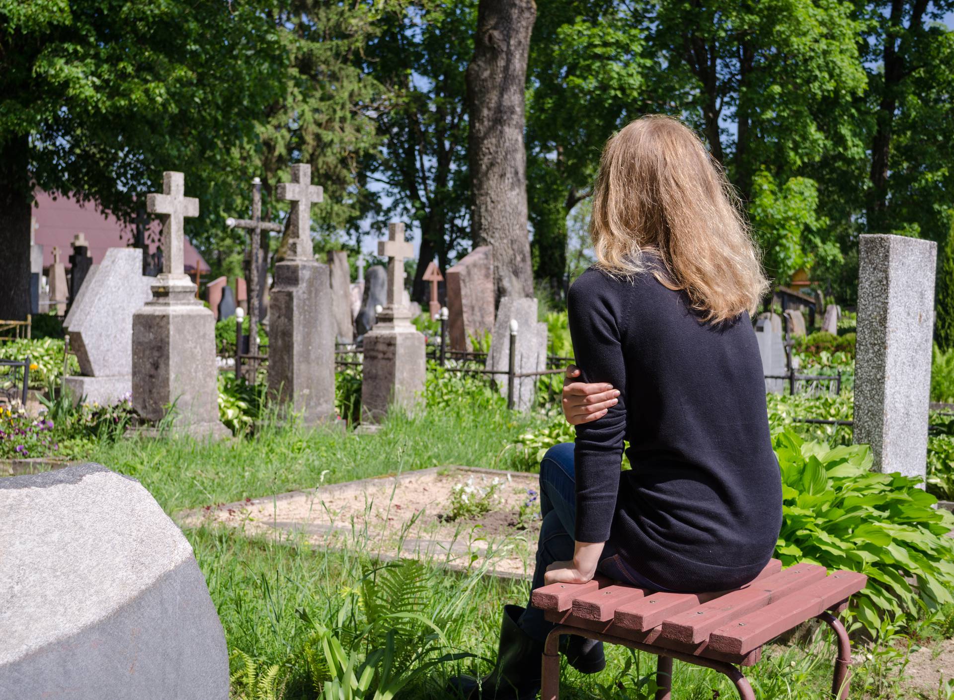 Sorrow woman near father husband tomb in cemetery