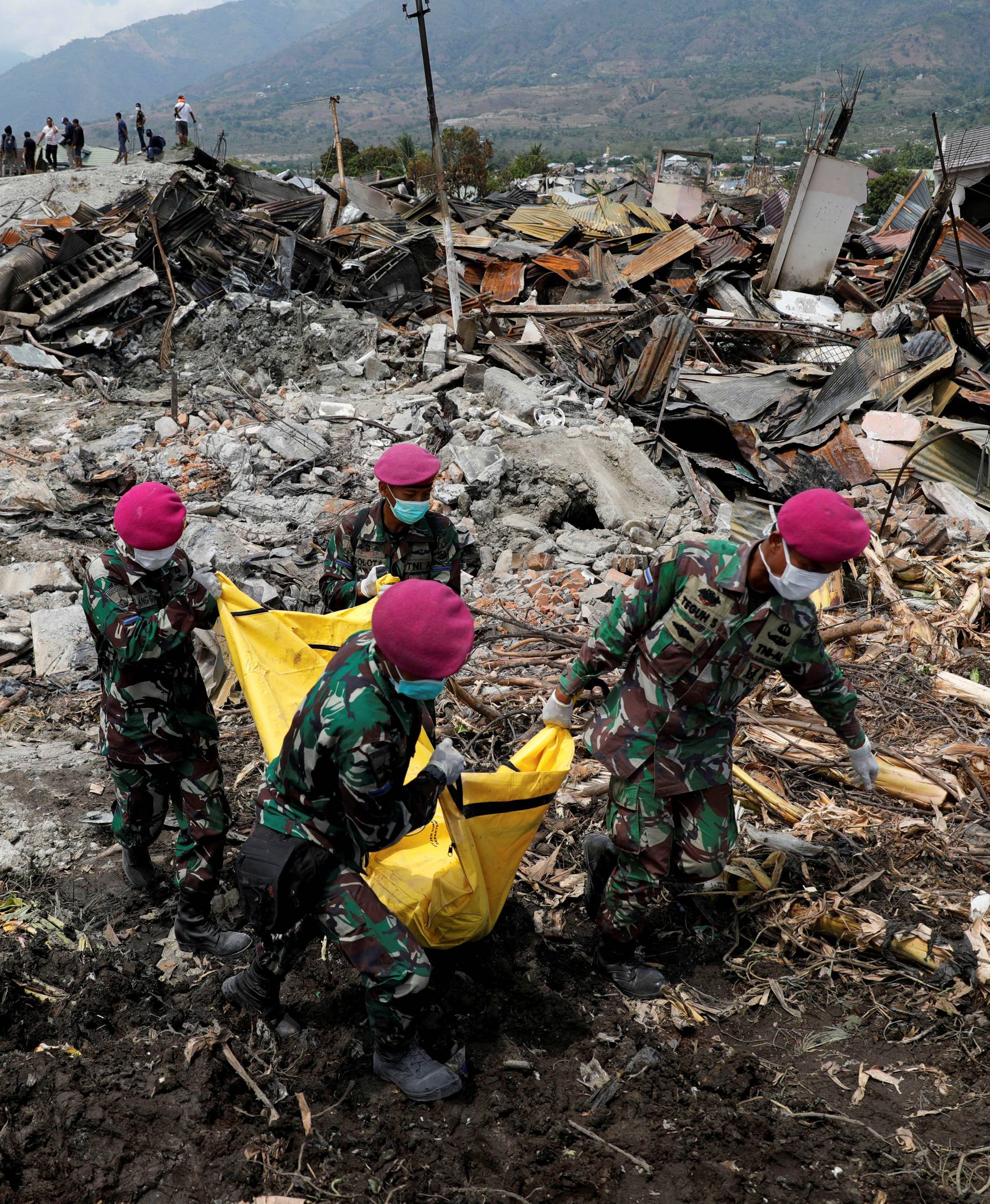 Indonesian soldiers carry a dead body from the ruins of houses after an earthquake hit Balaroa sub-district in Palu