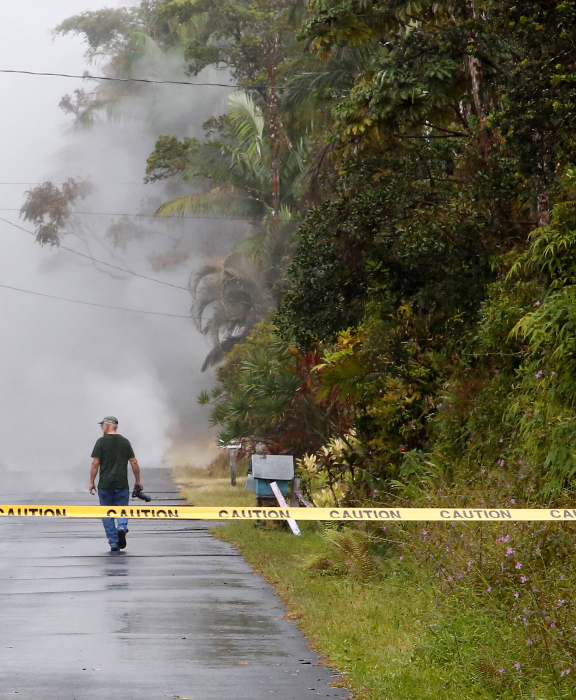 Leilani Estates resident Delance Weigel, 71, walks toward steam and sulfur dioxide gas emerging from a crack in the ground near his home during ongoing eruptions of the Kilauea Volcano