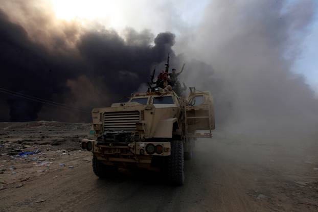 Iraqi army personnel ride on a military vehicle in Qayyarah 
