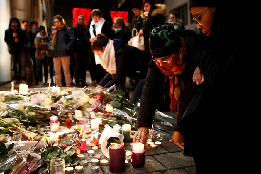 People cry as they light candles in tribute to the victims of the deadly shooting in Strasbourg