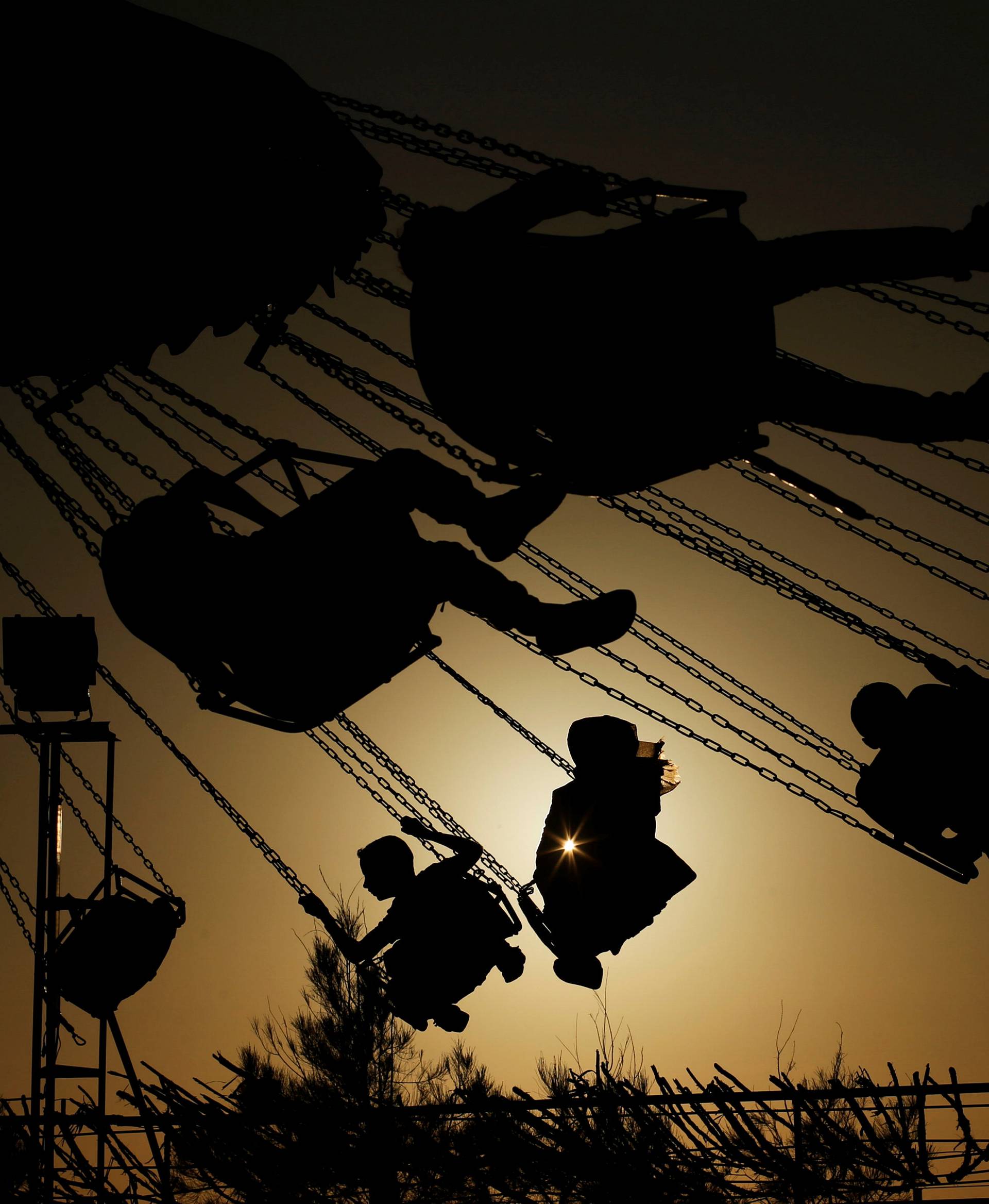 Palestinians enjoy a ride in an amusement park on the last day of Eid al-Fitr celebrations, in Gaza City