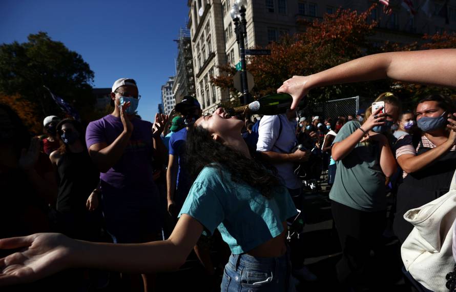 People react as media announce that Democratic U.S. presidential nominee Joe Biden has won the 2020 U.S. presidential election in Washington