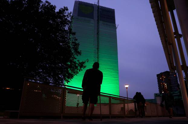 Grenfell Tower is seen covered and illuminated with green light one year after the tower fire in London