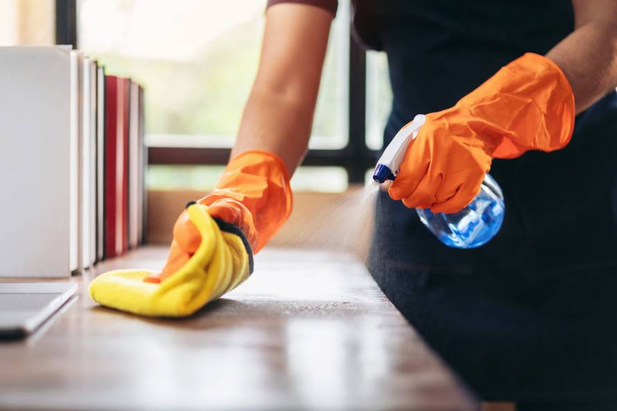 Housekeeper,Man,In,Orange,Rubber,Gloves,Using,A,Clean,Spray