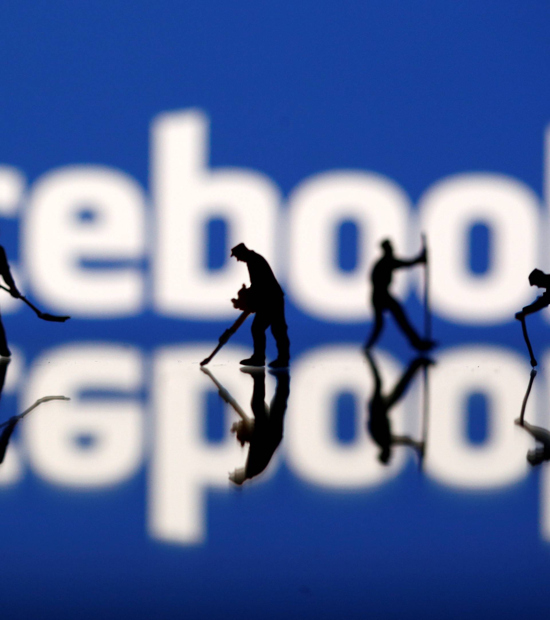 Figurines are seen in front of the Facebook logo in this illustration