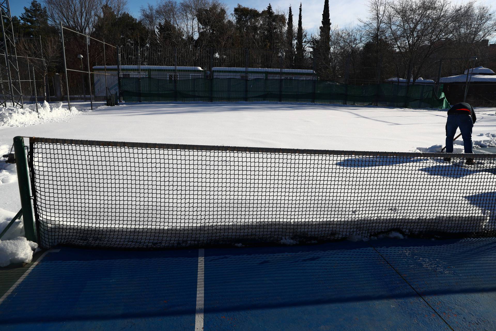 A worker cleans a municipal tennis court after a heavy snowfall in Madrid