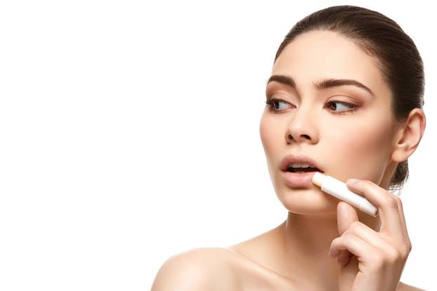 girl applying pink lipstick isolated on white