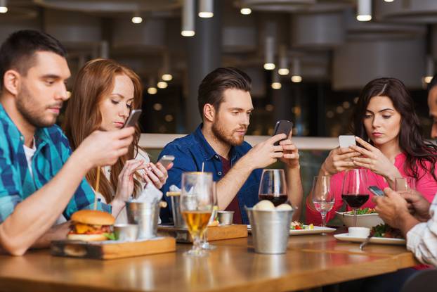 Friends,With,Smartphones,Dining,At,Restaurant