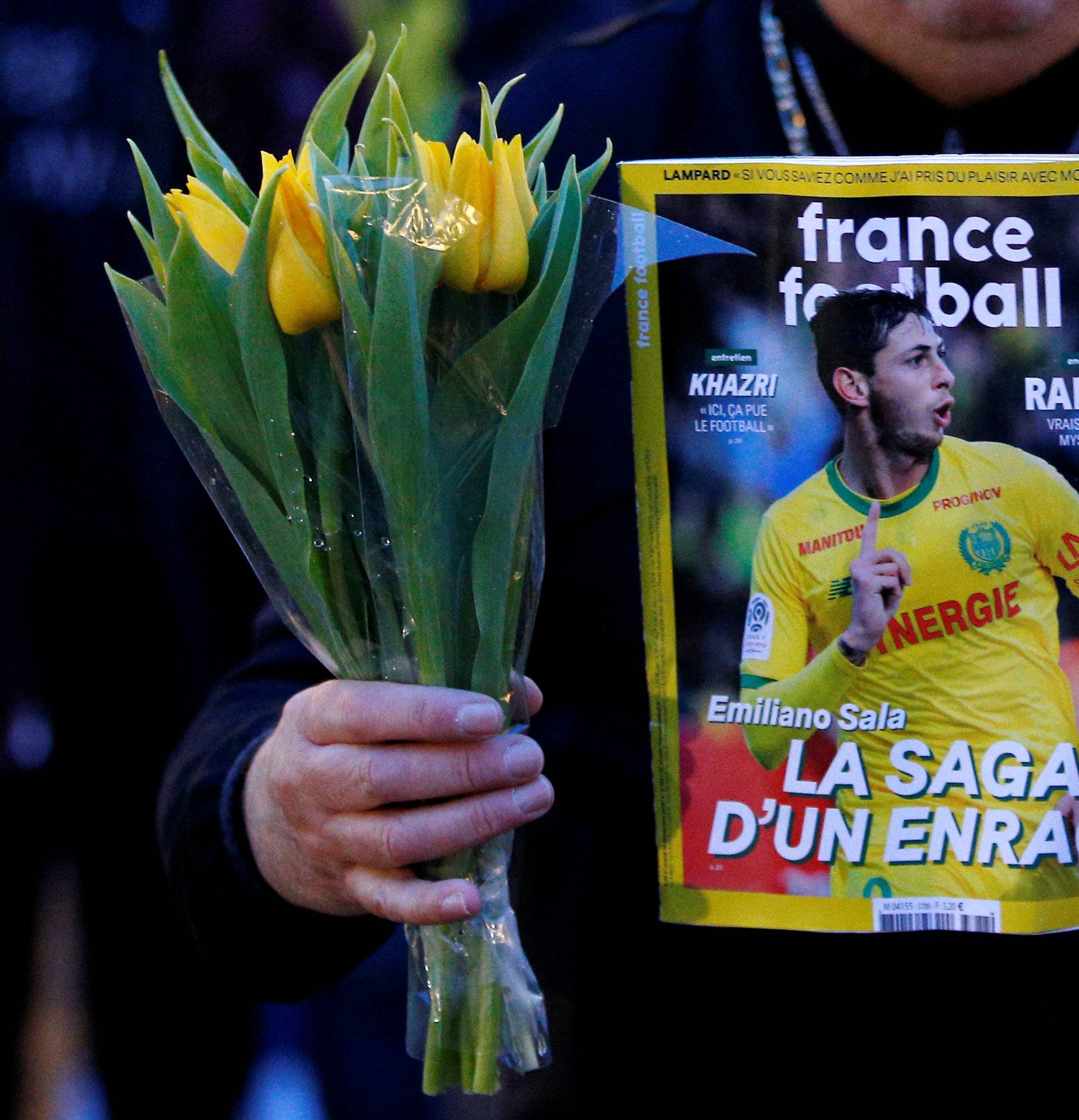 A man holds a sports magazine and yellow tulips as fans gather in the Nantes city center after news that newly-signed Cardiff City soccer player Emiliano Sala was missing after the light aircraft he was travelling in disappeared between France and England