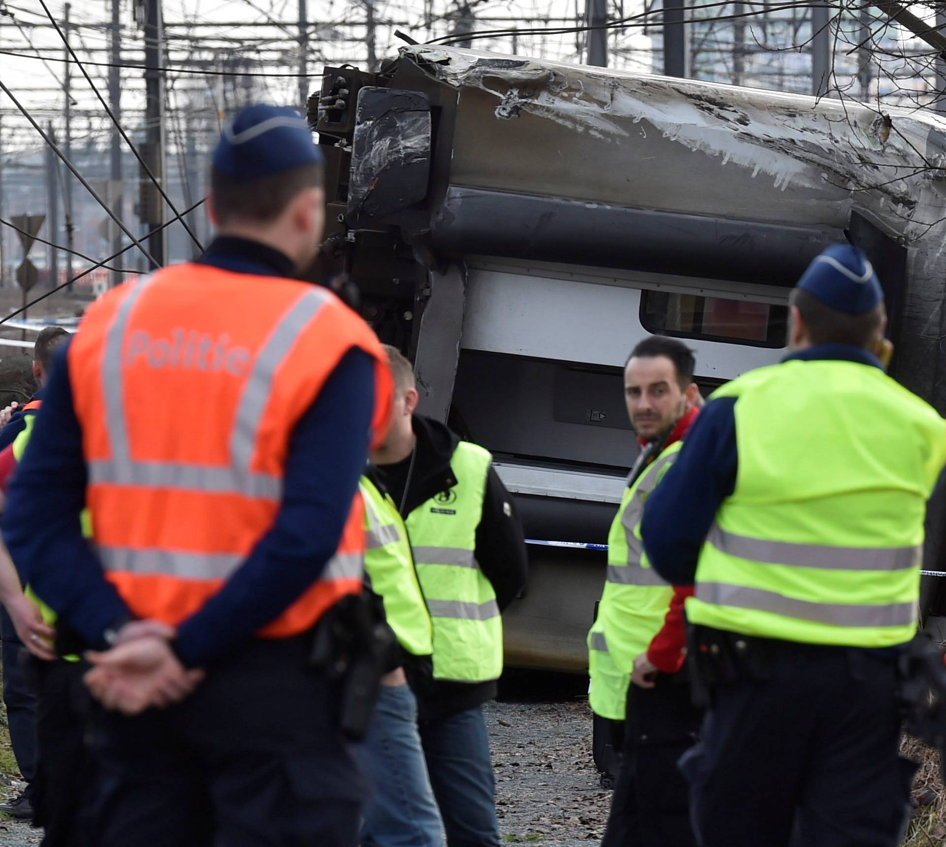 Rescuers and police officers stand next to the wreckage of a passenger train after it derailed in Kessel-Lo near Leuven