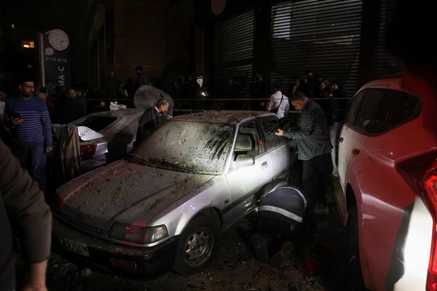 People gather near a damaged car following an explosion at Beirut suburb of Dahiyeh