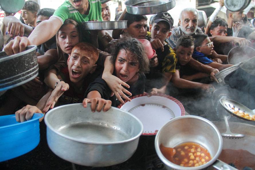 FILE PHOTO: Palestinians gather to receive food cooked by a charity kitchen, amid the Israel-Hamas conflict, in the northern Gaza Strip