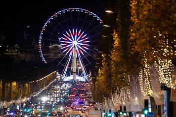 Christmas holiday lights hang from trees to illuminate Champs Elysees avenue in Paris as rush hour traffic fills the avenue leading down to the Giant Ferris Wheel at place de la Concorde in Paris