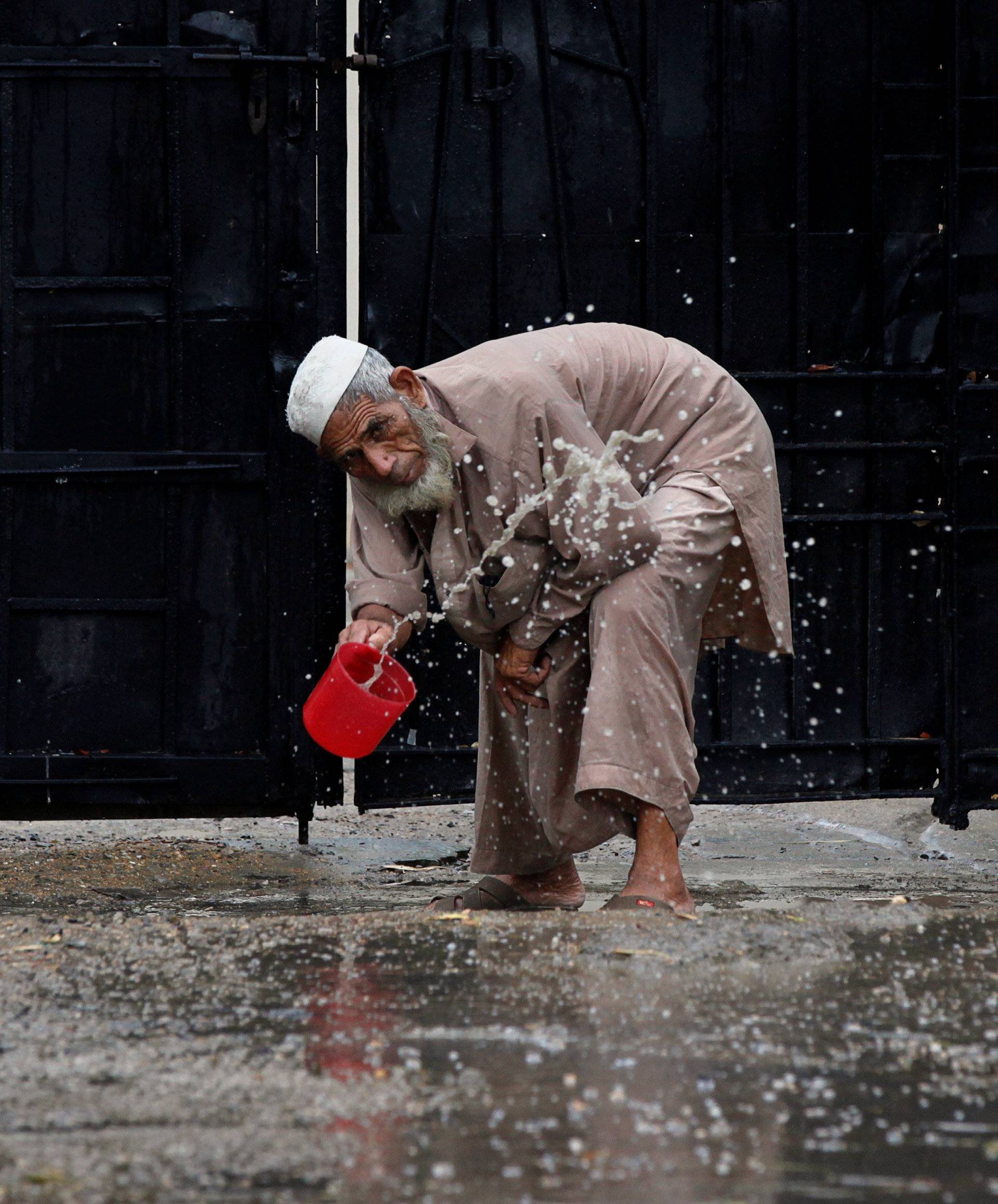 A man clears water from the entrance of an office after rain in Karachi,