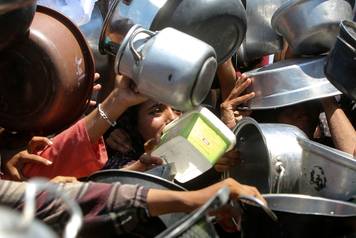 Palestinians wait to receive food from a charity kitchen, amid a hunger crisis, in Khan Younis
