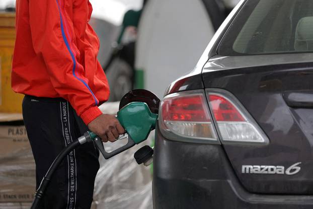 FILE PHOTO: A person uses a petrol pump at a gas station as fuel prices surged in Manhattan, New York City