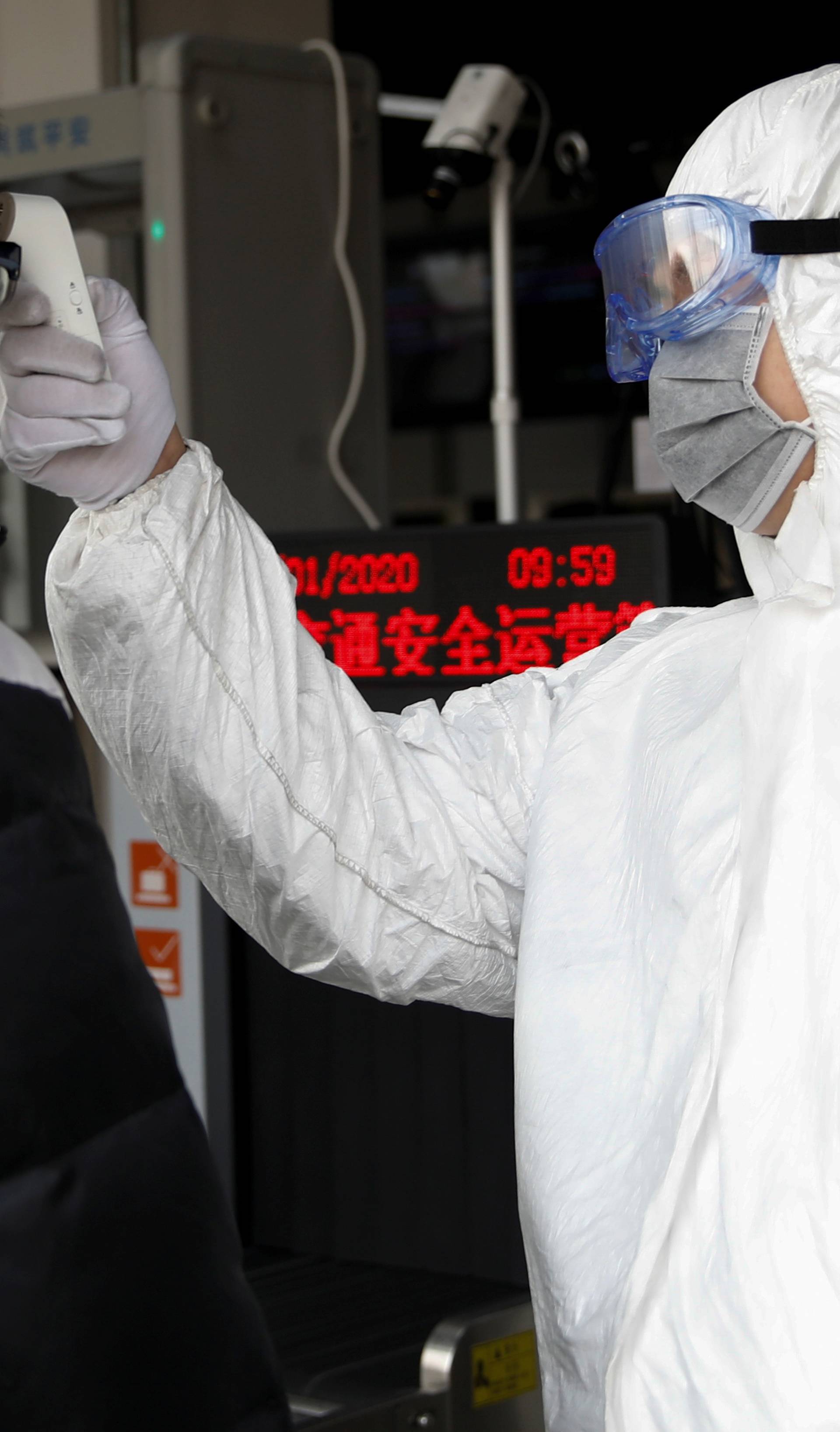 A worker in protective suit uses a thermometer to check the temperature of a man while he enters the Xizhimen subway station, as the country is hit by an outbreak of the new coronavirus, in Beijing