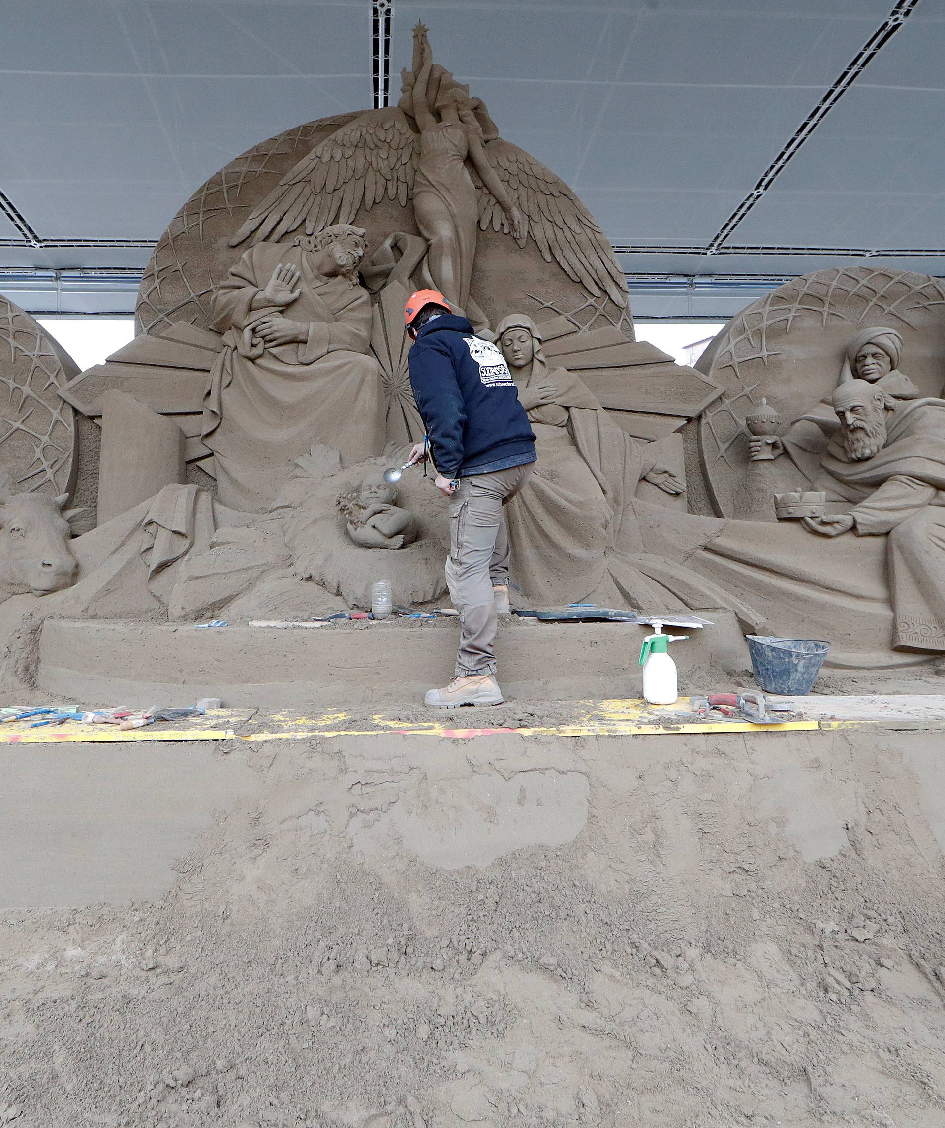 An artist works on a sand sculpture representing part of nativity scene in St. Peter's square at the Vatican