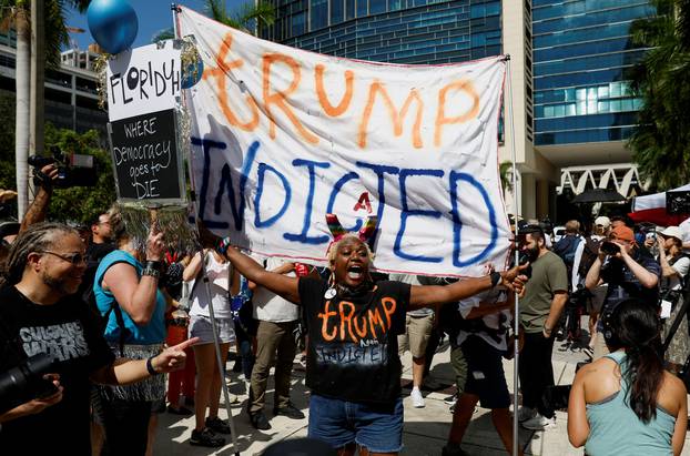 A person holds a banner near The Wilkie D. Ferguson Jr. United States Courthouse, in Miami