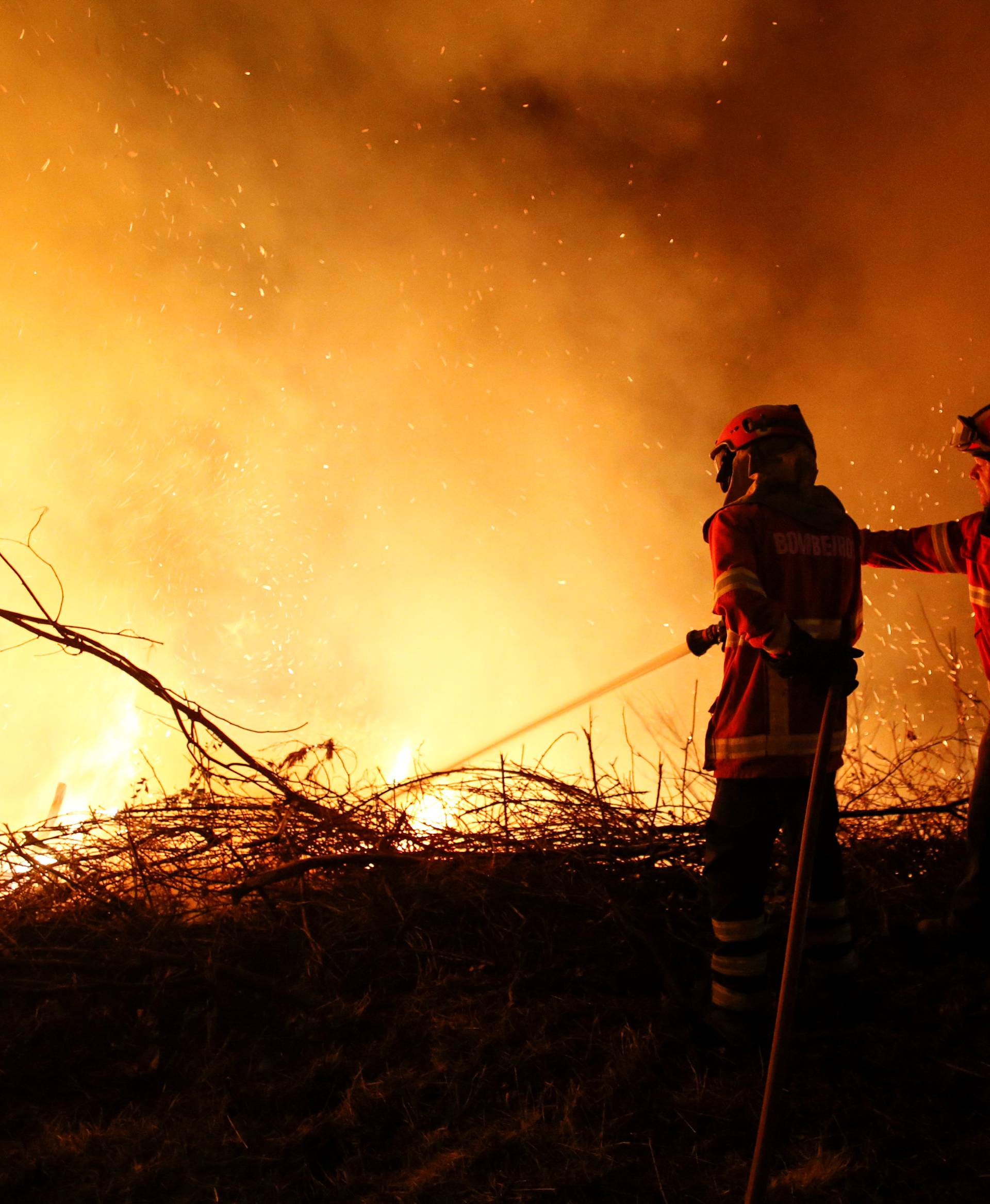 Firefighters try to extinguish flames from a forest fire in Cabanoes near Lousa