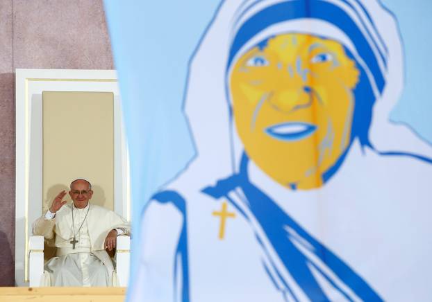 Pope Francis waves as a picture of Mother Teresa is seen during World Youth Days at Blonia Park in Krakow