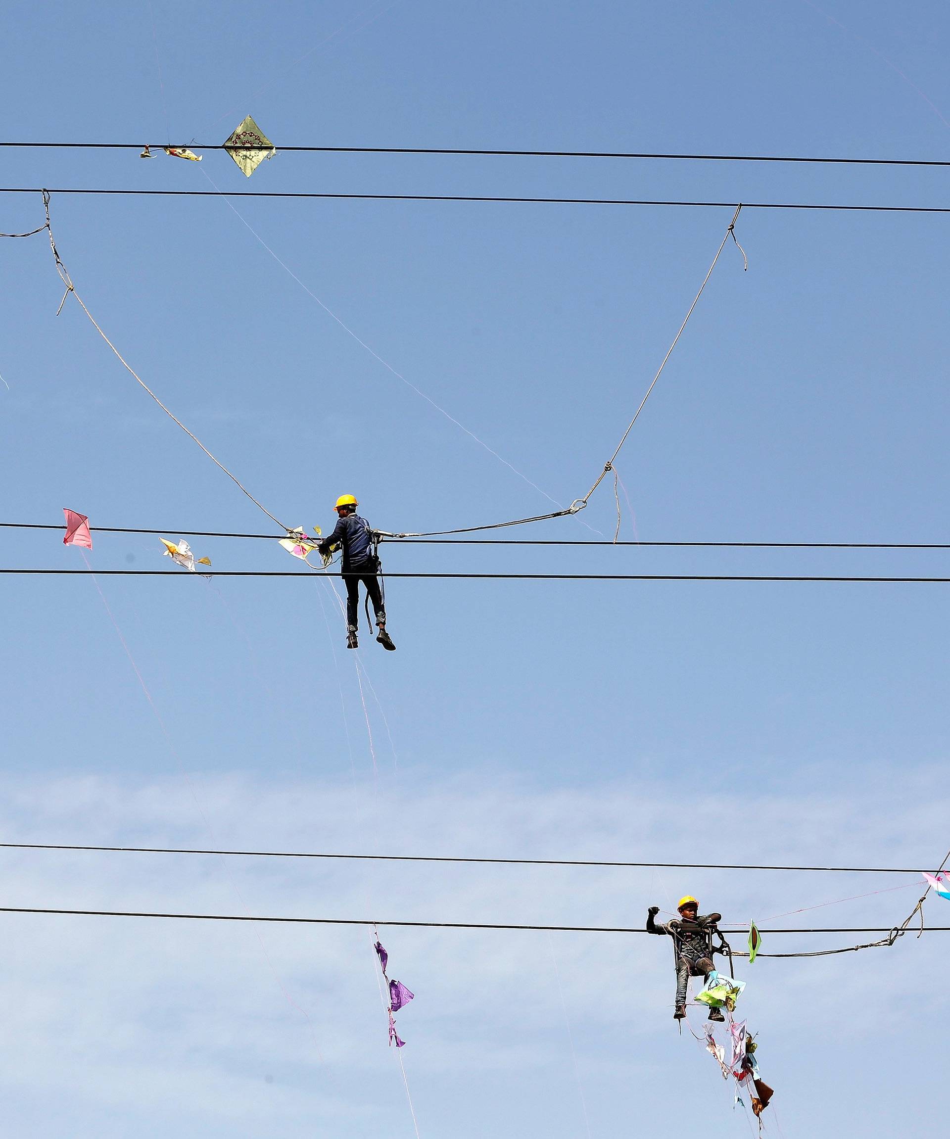 Workers of Torrent Power Limited remove kites tangled up in electric power cables after the end of the kite flying season in Ahmedabad