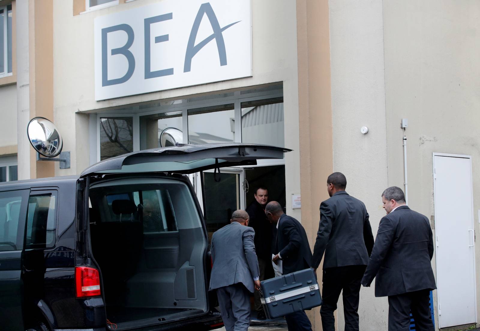 Men unload a case from a diplomatic car of the Ethiopian Embassy arrives at the headquarters of France's BEA air accident investigation agency in Le Bourget