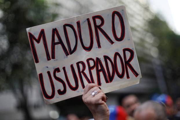 A woman holds a sign as she gathers in support of Venezuela