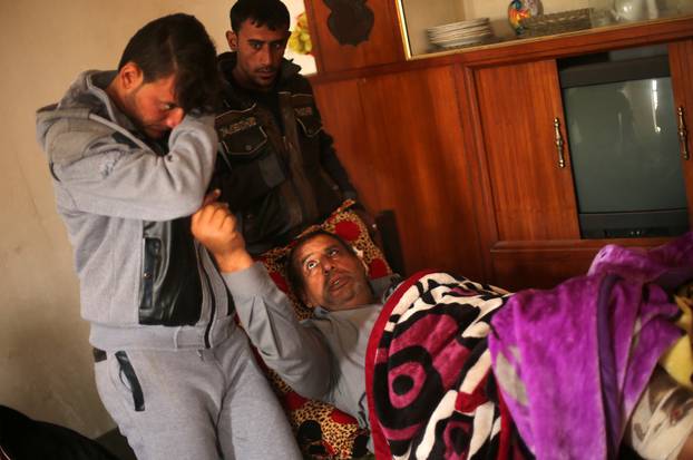 Azad Hassan, whose hand was chopped off by Islamic State militants, cries as he stands beside his wounded father in a house at Nimrud village, south of Mosul