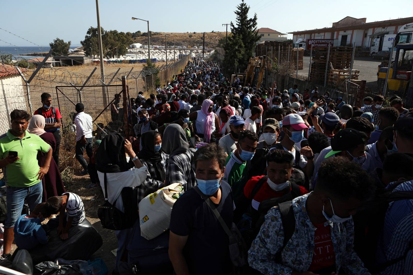 Refugees and migrants from the destroyed Moria camp wait to board busses to the port from where they will be transferred to the mainland, on the island of Lesbos