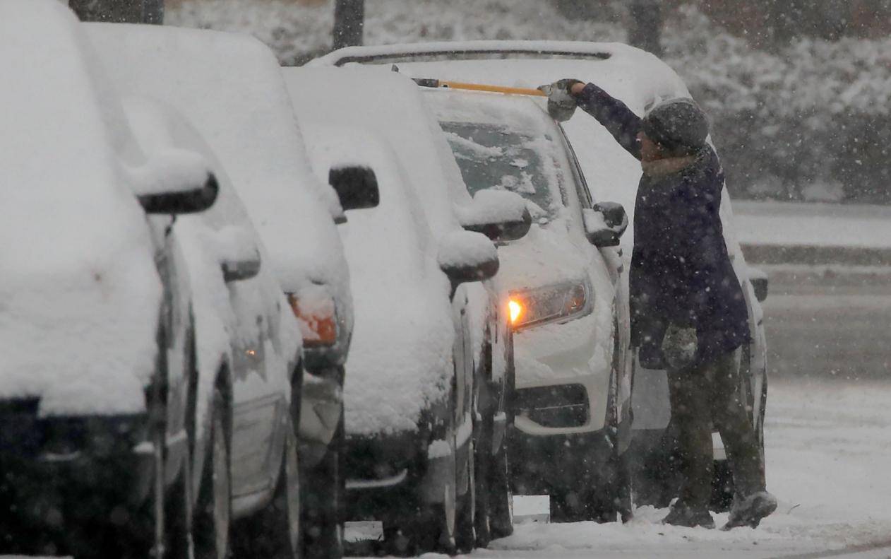 A local resident removes snow from a car during a winter storm in Washington