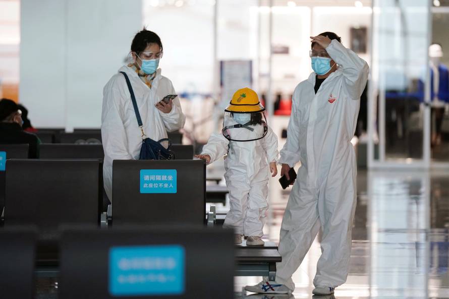 Travellers in protective suits are seen at Wuhan Tianhe International Airport in Wuhan