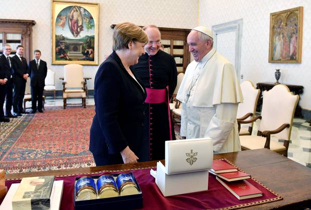 German Chancellor Merkel exchanges gifts with Pope Francis during a meeting at the Vatican