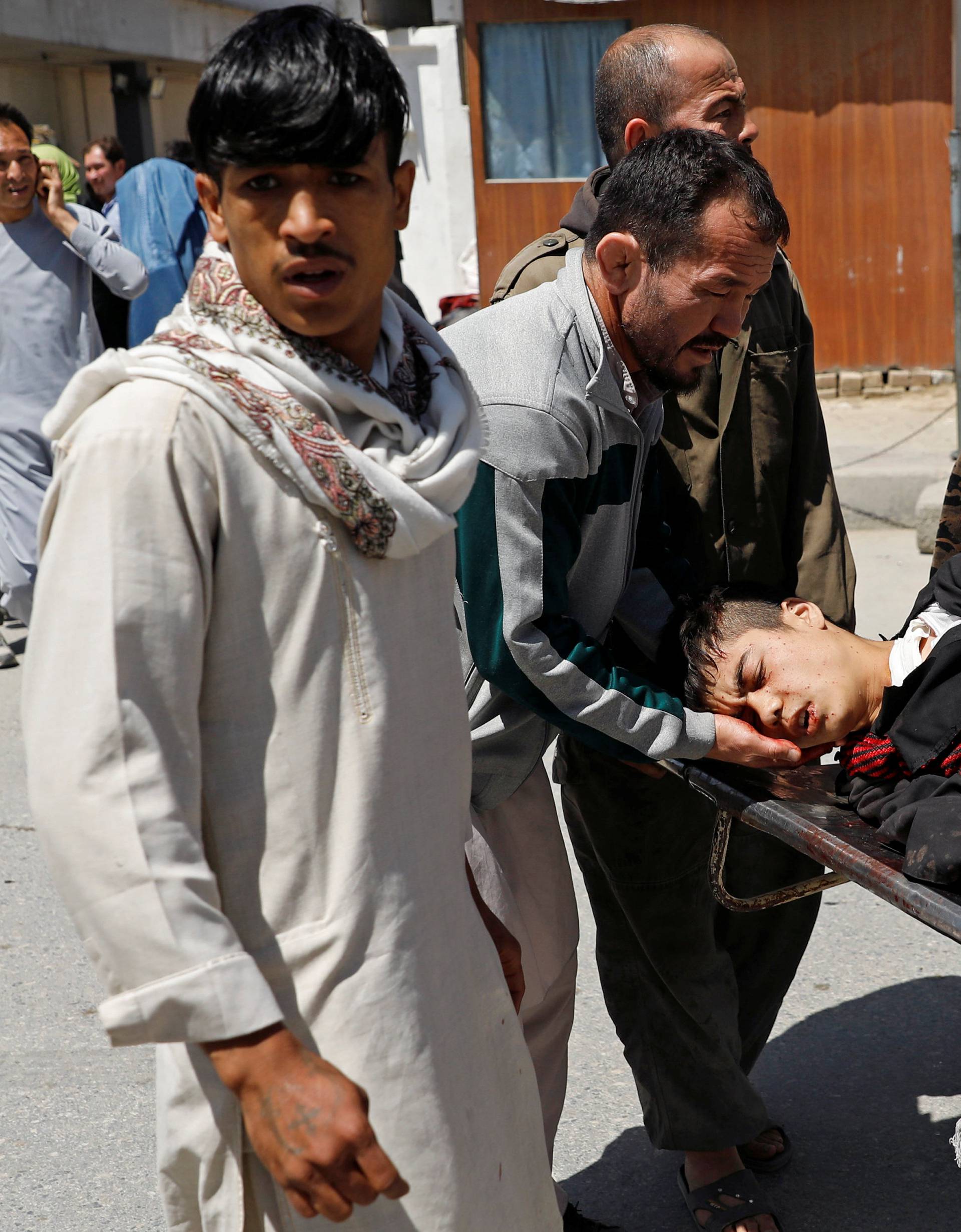 Relatives carry an injured man outside a hospital after a suicide attack in Kabul
