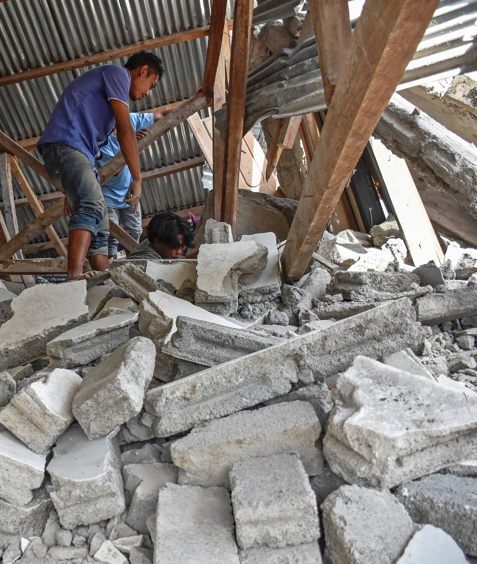 A villager walks through the ruins of a collapsed house during a search for the equipment of Malaysian tourists who died during the earthquake at the Sembalun Selong village in Lombok Timur