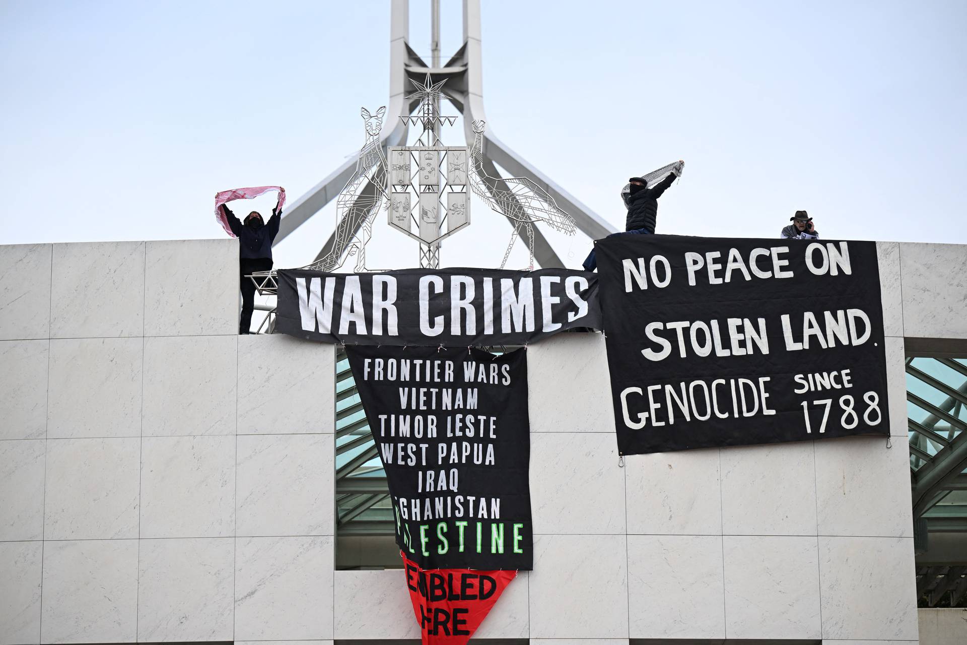 Pro-Palestinian protesters hang banners from the top of Parliament House in Canberra