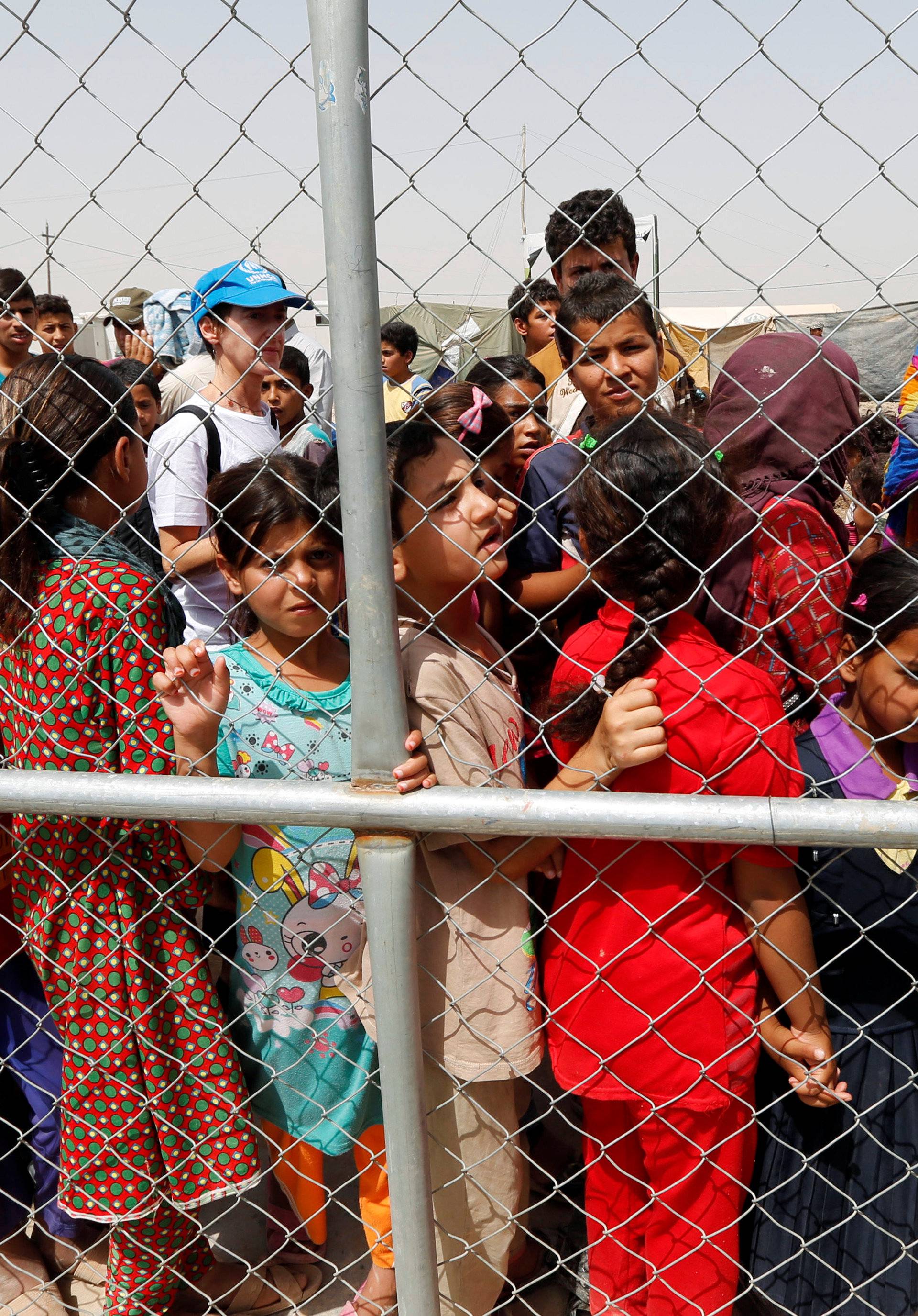 Displaced people look through barbed wire during World Refugee Day celebrations at Al-salam refugee camp in Baghdad