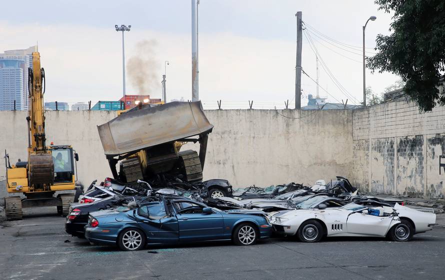 A bulldozer destroys condemned smuggled luxury cars worth 61,626,000.00 pesos during the 116th Bureau of Customs founding anniversary in Manila