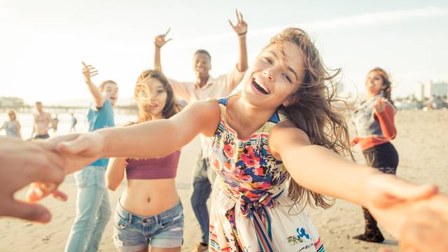 Group of friends having fun and dancing on the beach