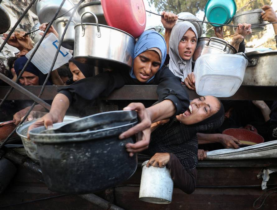 Palestinians wait to receive food from a charity kitchen, amid a hunger crisis, in Gaza City