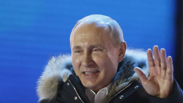 Russian President and Presidential candidate Putin gestures as he attends a rally and concert marking the fourth anniversary of Russia's annexation of the Crimea region, in Moscow