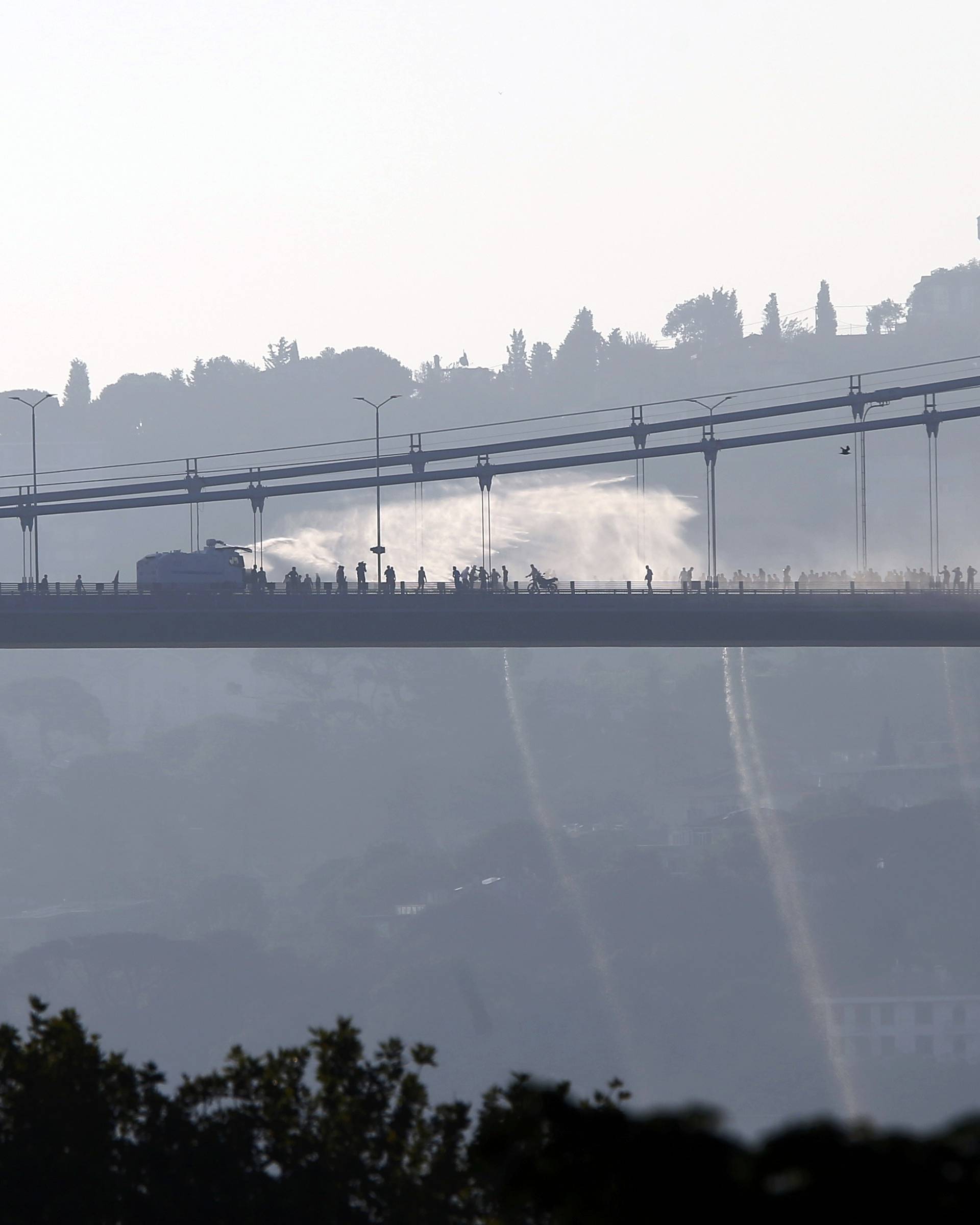 A police armored vehicle uses a water cannon to disperse anti-government forces on Bosphorus Bridge in Istanbul