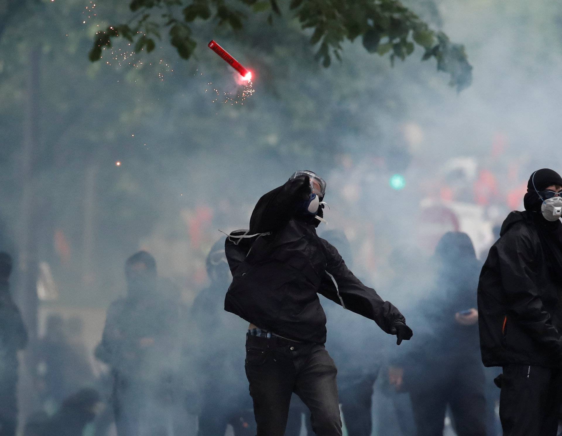 A protester throws a safety flare during clashes with French riot police at the May Day labour union rally in Paris