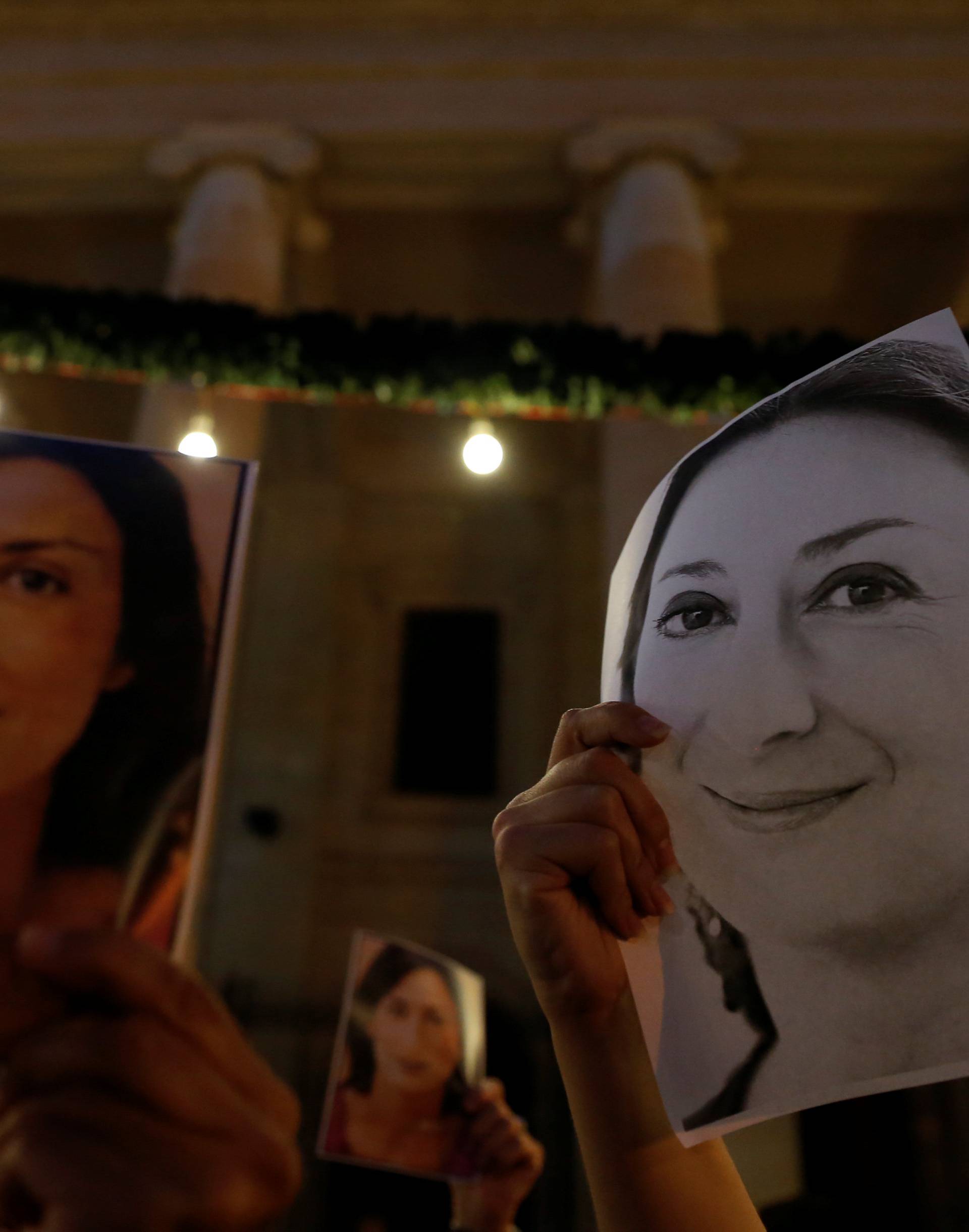 People hold photos of assassinated anti-corruption journalist Daphne Caruana Galizia during a vigil to mark eleven months since her murder in a car bomb, outside the Courts of Justice in Valletta