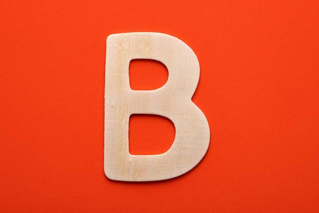 Alphabet letter B - White wood piece on orange foamy background
